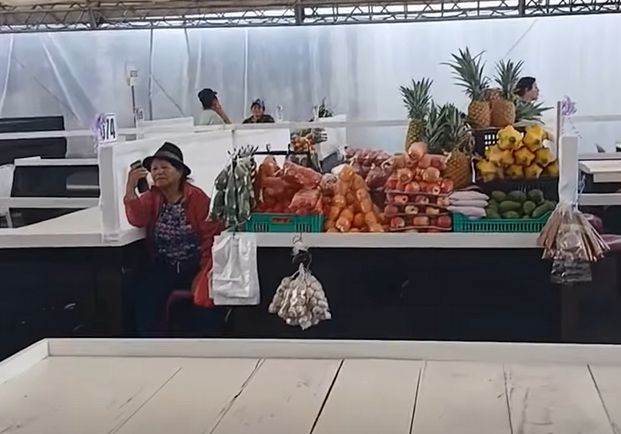 Puesto surtido con piñas, zanahorias, cebollas y aguacates