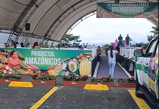 Entrada del mercado techado con banners «Hermanos productores bienvenidos» y «Productos amazónicos»